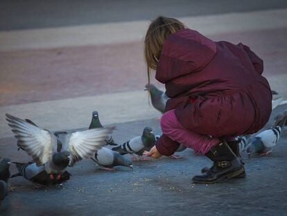 Una nena d&oacute;na menjar als coloms a la pla&ccedil;a Catalunya.