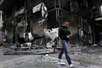 Un hombre pasa ante una tienda incendiada durante las protestas en Latakia.
