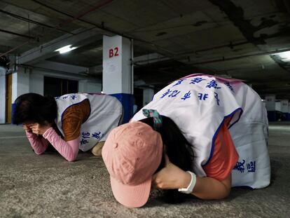 People demonstrate taking shelter with their hands covering their eyes and ears while keeping their mouth open, during a drill at a basement parking lot that will be used as an air-raid shelter in the event of an attack, in Taipei, Taiwan, July 22, 2022. REUTERS/Ann Wang