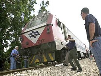 La policía israelí y trabajadores del tren inspeccionan los daños causados por el atentado.