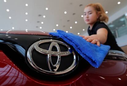 Una mujer limpia un vehículo de la marca japonesa Toyota.