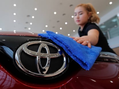 Una mujer limpia un vehículo de la marca japonesa Toyota.