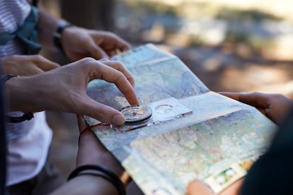 Unas manos sosteniendo una brújula y un mapa en el bosque.