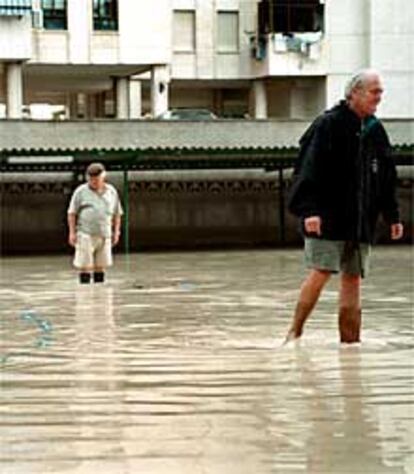 Dos vecinos, ayer, en una zona inundada de la playa de San Juan.