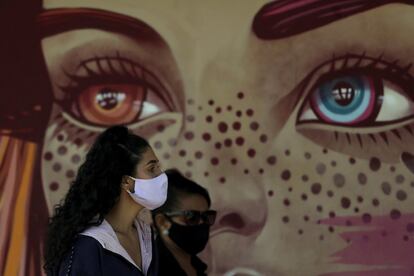 Dos jóvenes, protegidas con mascarillas, esperan hacerse una prueba de detección de coronavirus en la cancha de baloncesto de una escuela pública de Brasilia.