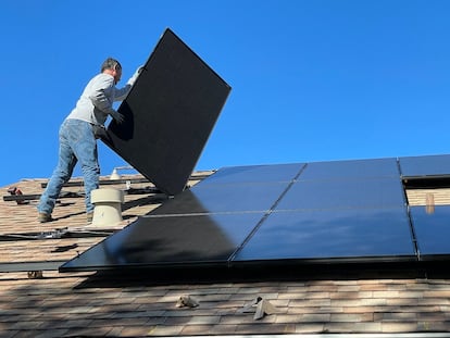 Un operario instala placas fotovoltaicas en un tejado.