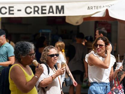 Tres turistas pasean por las calles de Málaga comiendo unos helados.