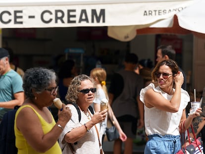 Tres turistas pasean por las calles de Málaga comiendo unos helados.