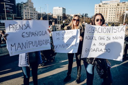 Tres mujeres sostienen diferentes pancartas durante una manifestación negacionista, el 11 de diciembre de 2021 en Madrid.