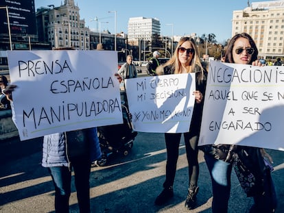 Three women hold up placards during an anti-vaccination protest in Madrid, on December 11, 2021.