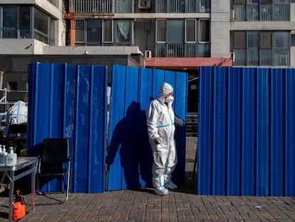 A worker with protective equipment in a neighborhood under confinement in Beijing on Monday.