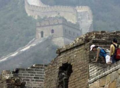 Dos turistas observan una parte dañada de la Gran Muralla.