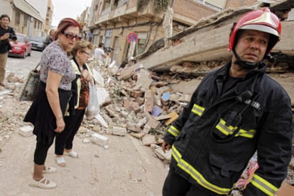 Un bombero y varios vecinos, delante de los escombros a los que quedó reducido un edificio de la calle del Infante don Juan Manuel.