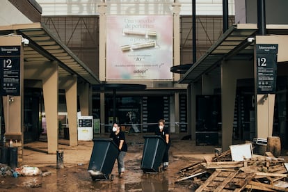 Dos trabajadoras sacan cubos de basura del centro comercial Bonaire en Aldaia, este domingo. 