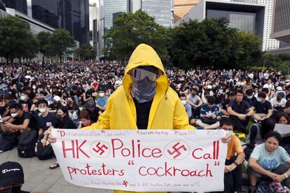 Un manifestante sostiene una pancarta ilustrada con esvásticas en la que se lee "la policía de Hong Kong califica a los manifestantes de cucarachas", durante el primer día del curso académico, en Parque Tamar frente al Ministerio de Marina de Hong Kong (China).