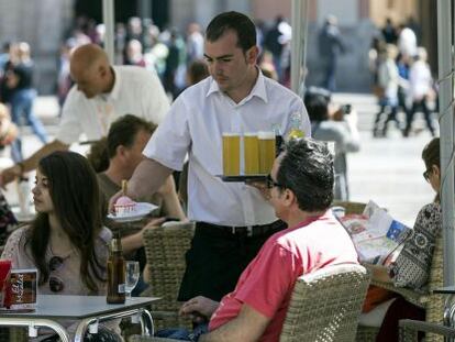 Un camarero sirve bebidas, en una terraza en la plaza de la Virgen de Valencia.