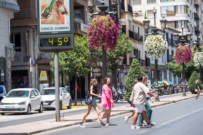 Unas personas caminan junto a un termómetro exterior que indica 45 grados en una calle del centro de Granada este martes.