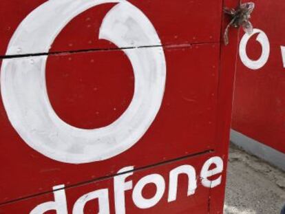 Un hombre habla con su m&oacute;vil al lado de un logotipo de Vodafone.