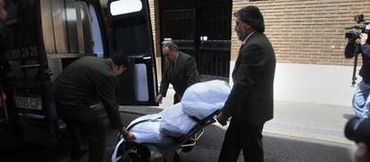Empleados de la funeraria trasladan el cuerpo de la mujer.