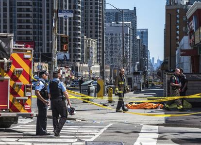 Agentes de la policía, junto a un cuerpo cubierto en la acera, después de que una camioneta arrollara a una multitud de peatones en Toronto.