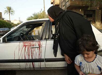 Una iraquí mira dentro del coche en el que ayer murieron dos mujeres por los disparos de agentes de seguridad privados en Bagdad.