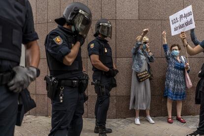 Las protestas se han reproducido por casi todos los puntos afectados por las restricciones e incluso en áreas colindantes a las confinadas: esta mañana había convocadas manifestaciones en Villaverde, Carabanchel, Ciudad Lineal, Arganzuela, Getafe, Parla y Fuenlabrada. En la imagen, agentes de la policñia junto a dos vecinas en Puente de Vallecas, este domingo.