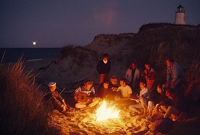 Un grupo de amigos charla alrededor de una hoguera cerca del faro de Great Point, en Nantucket.