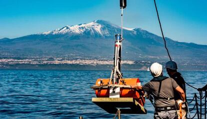 Dos miembros del equipo que investiga el Etna colocan instrumentos de medición en el agua.