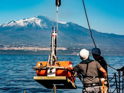 Dos miembros del equipo que investiga el Etna colocan instrumentos de medición en el agua.