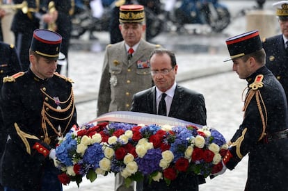 El presidente francés porta un ramo de flores como ofrenda ante la tumba del soldado desconocido bajo la intensa lluvia que caía en ese momento en el Arco de Triunfo de París.