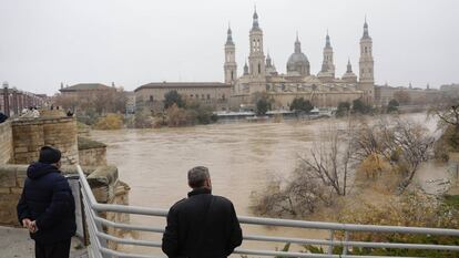 Varios vecinos de Zaragoza observan la crecida del río Ebro, este martes.