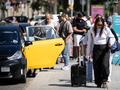Turistas con maletas en la plaza de Catalunya de Barcelona, donde hay paradas de taxi y del Aerobús, que une la ciudad con el aeropuerto.