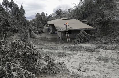 Un hombre limpia el techo de cenizas volcánicas en Boso-Boso, provincia de Batangas, sur de Filipinas, el martes 14 de enero de 2020. El volcán Taal arroja lava a media milla de altura y tiembla constantemente con terremotos mientras decenas de miles de personas huyen de las aldeas oscurecidas por una pesada nube de ceniza.