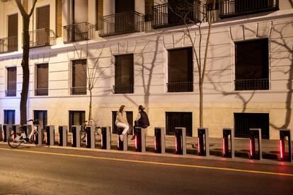 Dos chicas charlan sentadas en los puestos de Bicimad en una calle del centro de Madrid.