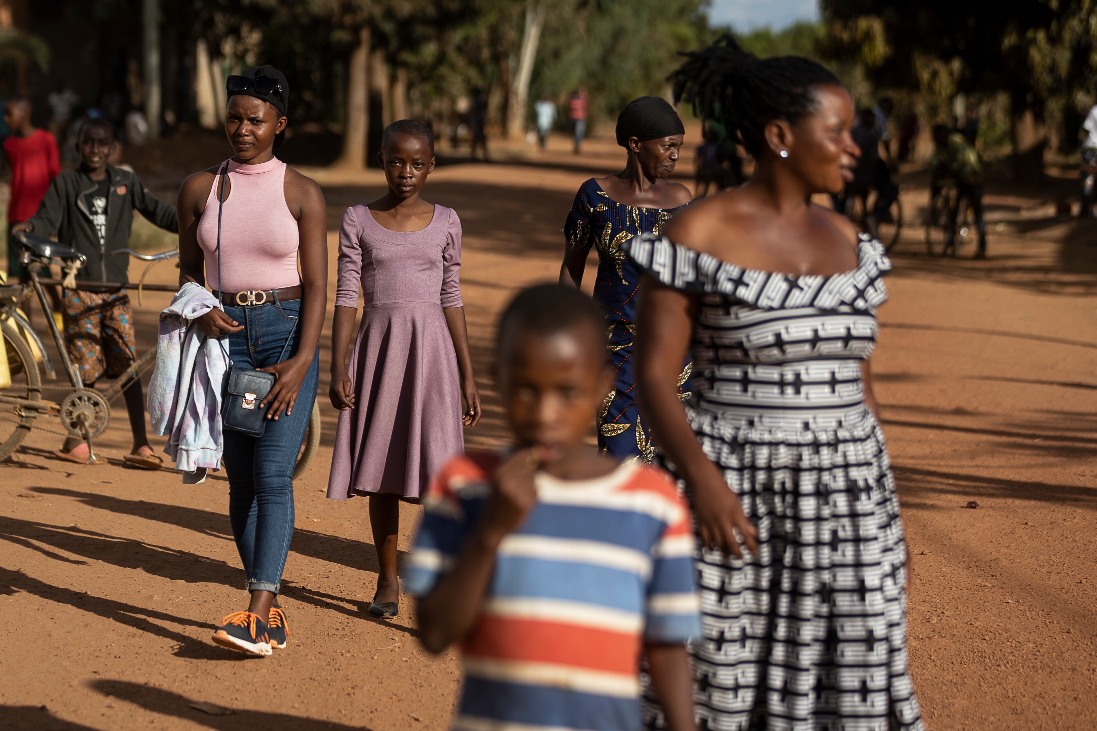 Bellefille, de 19 años, y Alliance, de 14, caminan junto a sus familias por las calles de Jurú, en el distrito ruandés de Bugesera. Las dos familias han participado en el programa de la ONG Interpeace, apoyado por el Gobierno ruandés y la Unión Europea y destinado a sanar el trauma social que aún perdura en comunidades, casi 30 años después del genocidio en el país africano.