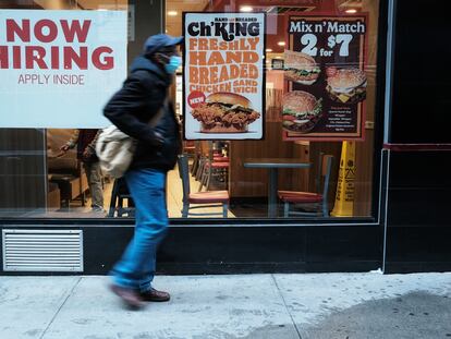 Una persona camina junto a un cartel que anuncia empleo en un restaurante de comida rápida en Nueva York.