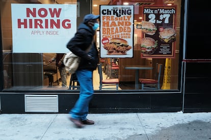 Una persona camina junto a un cartel que anuncia empleo en un restaurante de comida rápida en Nueva York.