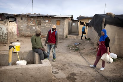 Tres personas esperaban para coger agua de la fuente en el asentamiento de Atochares, el miércoles. 