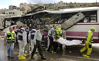 Policías y equipos sanitarios israelíes trasladan un cadáver del autobús que sufrió un atentado.