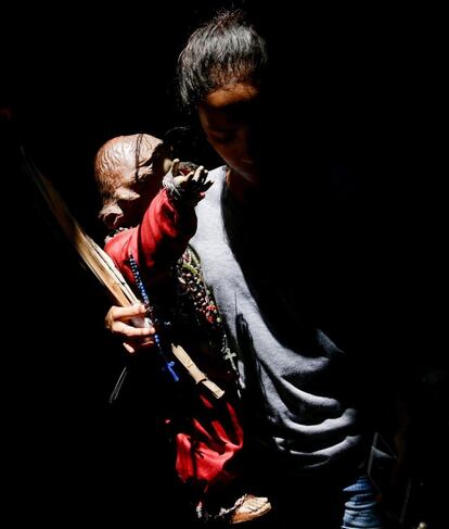 Una joven carga con una figura del Niño Jesús poco antes de la demolición de su vivienda en un barrio marginal de Manila (Filipinas).