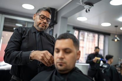 Augusto Rodríguez corta el pelo a un cliente en una barbería de Bogotá.
