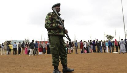 Un oficial de Policía keniano hace guardia mientras votantes hacen cola en el exterior de un colegio electoral, este martes en Nairobi.