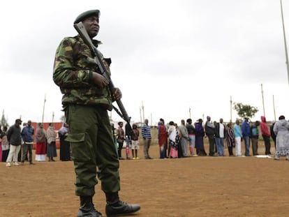 Un oficial de Policía keniano hace guardia mientras votantes hacen cola en el exterior de un colegio electoral, este martes en Nairobi.