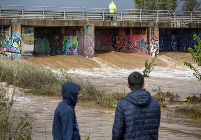 Dos jóvenes observan el caudal del río Palancia a su paso por Sagunto.