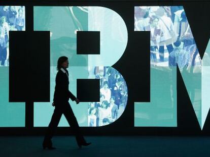 Una mujer pasea delante de un logo de IBM.