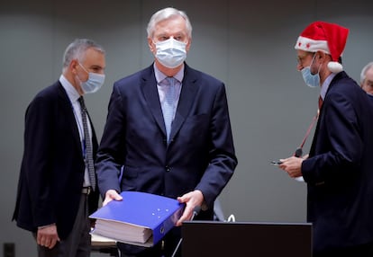 El negociador comunitario Michel Barnier (en el centro) deposita en la mesa el archivador con los cientos de páginas del acuerdo alcanzado con el Reino Unido en presencia de delegados griegos, durante la reunión extraordinaria convocada este viernes en Bruselas para explicar los detalles del acuerdo del Brexit.