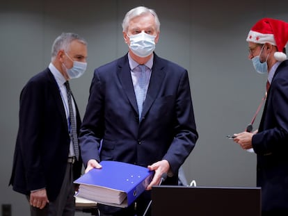 El negociador comunitario Michel Barnier (en el centro) deposita en la mesa el archivador con los cientos de páginas del acuerdo alcanzado con el Reino Unido en presencia de delegados griegos, durante la reunión extraordinaria convocada este viernes en Bruselas para explicar los detalles del acuerdo del Brexit.