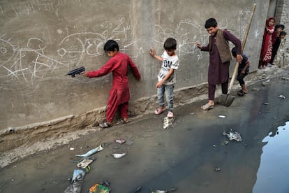 Niños tratan de pasar por una calle en la que se ha vaciado una fosa séptica en un barrio próximo a la zona de Sarai Shamali de Kabul.                            