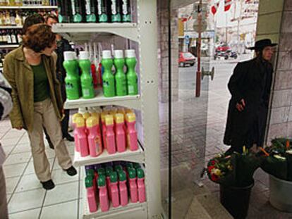 Una mujer israelí mira artículos en un supermercado. Fuera de la tienda, un judío ultraortodoxo.