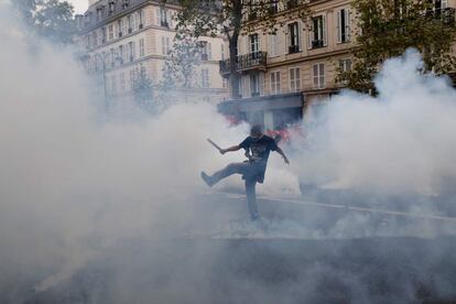 Un manifestante patea el gas lacrimógeno lanzado por la policía antidisturbios durante una manifestación contra la reforma laboral, en París.